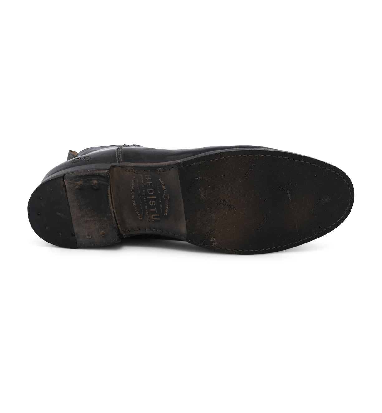 Bottom view of a worn leather ankle boot with visible scuff marks and a partially visible Bed Stu brand name on the insole.