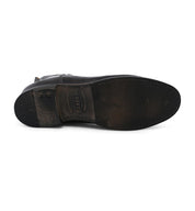 Bottom view of a worn leather ankle boot with visible scuff marks and a partially visible Bed Stu brand name on the insole.