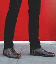 A man in a suit and tie standing in front of a Leonardo wall by Bed Stu.