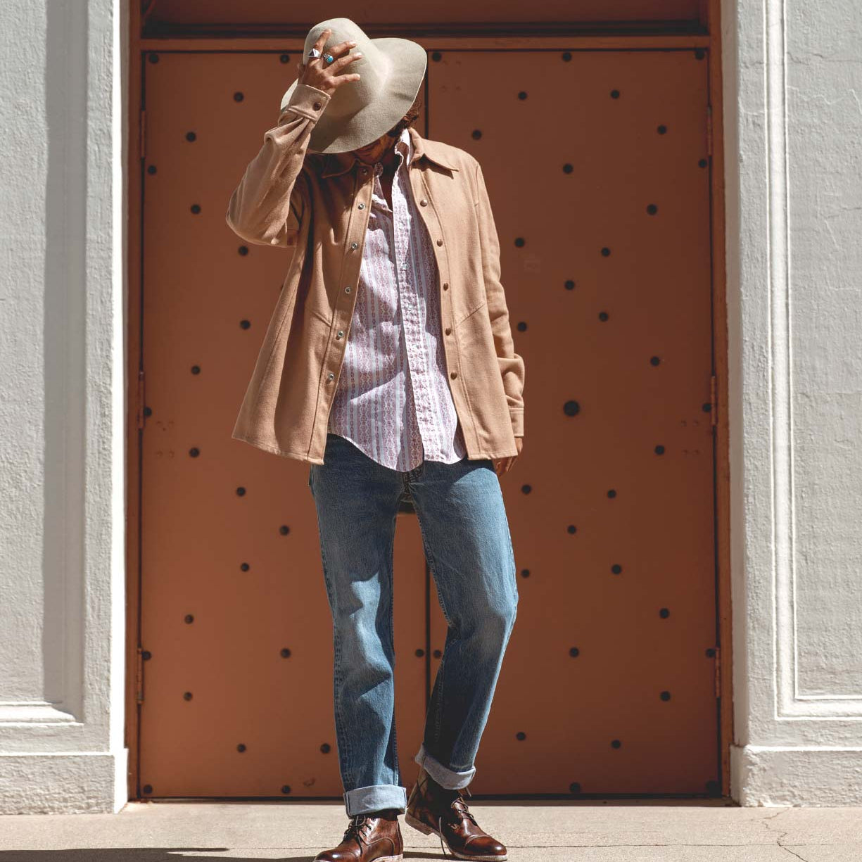 A man in a Bed Stu hat and jeans standing in front of a Leonardo door.