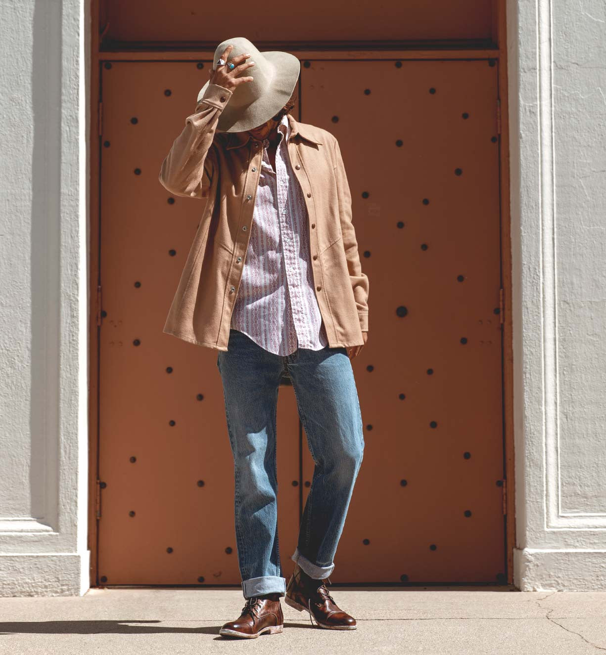A man in a Bed Stu hat and jeans standing in front of a Leonardo door.
