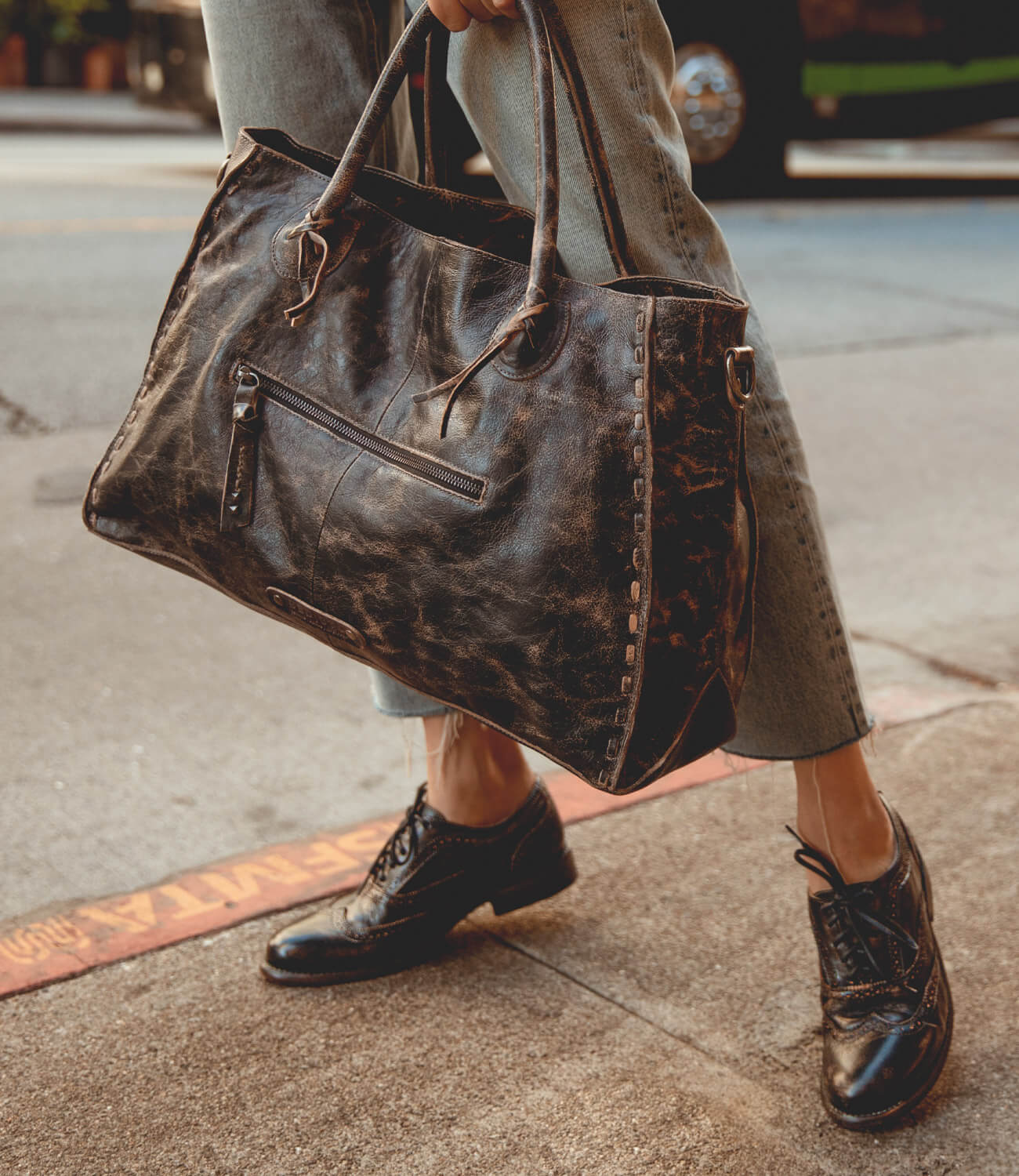 A woman on the street with a black Bed Stu Lita shoes and black leather bag.