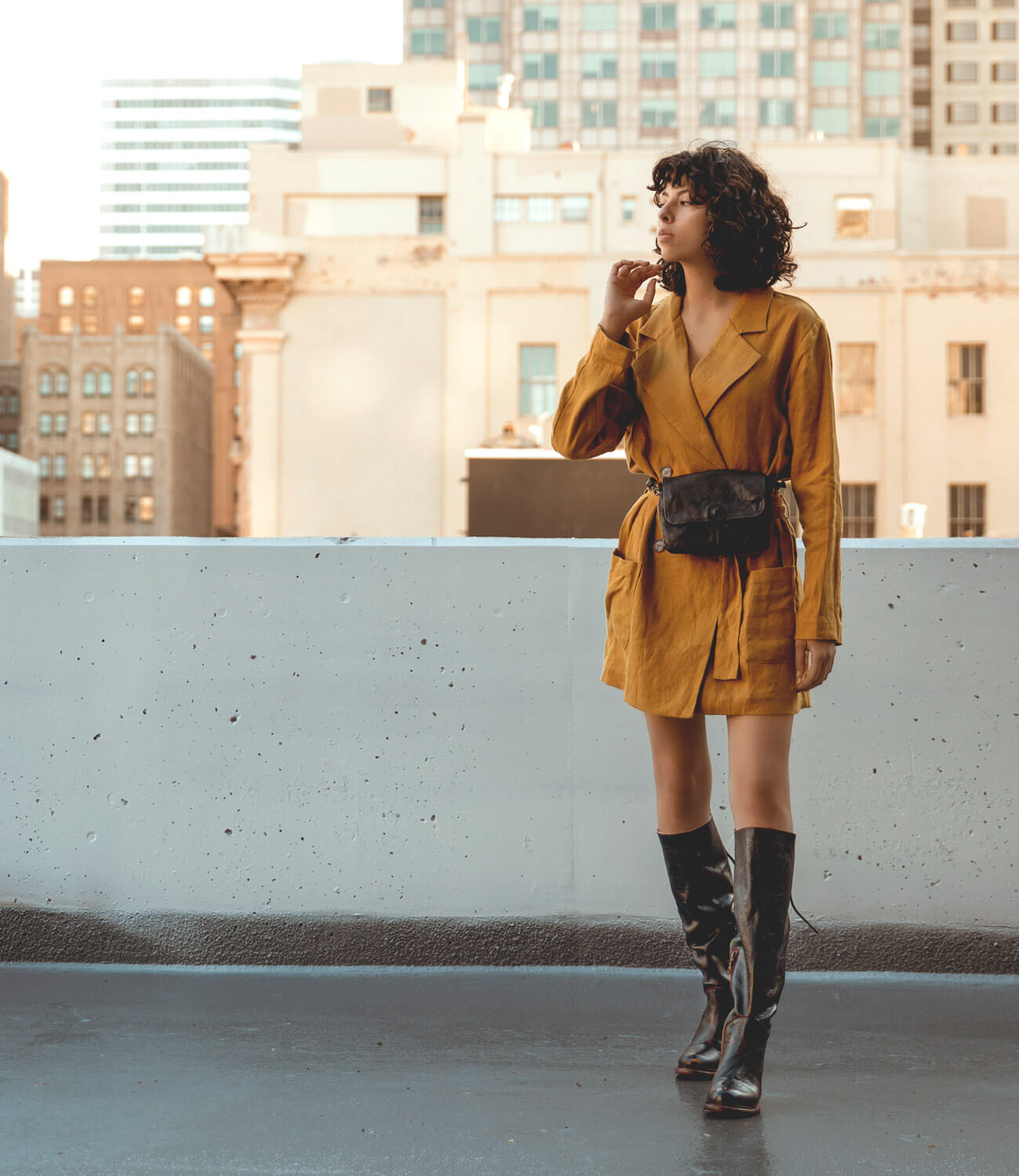 A woman in a yellow Manchester coat and Bed Stu boots is standing on a rooftop.