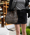 A woman wearing a black skirt and a grey Bed Stu Tahiti purse.