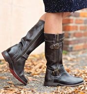 A woman wearing a pair of black leather Bed Stu Gogo Lug Wide Calf boots.