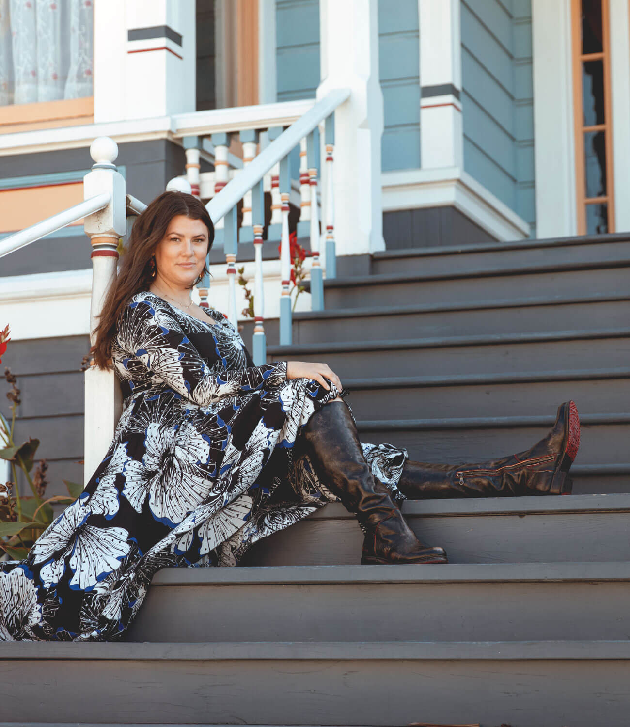 A woman sitting on the steps of a house wearing the Bed Stu Manchester Wide Calf boots.