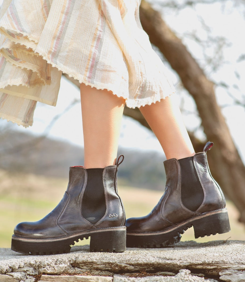 A woman is standing on a rock and wearing Bed Stu's Valda Hi chelsea boots.