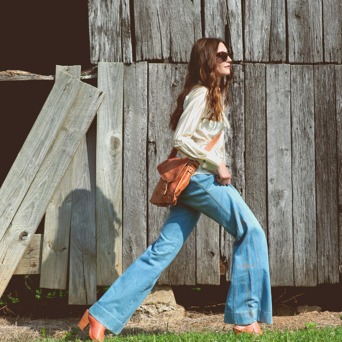 A woman walking wearing Venice Beach tan leather messenger bag from Bed Stu.