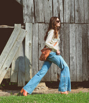 A woman walking wearing Venice Beach tan leather messenger bag from Bed Stu.