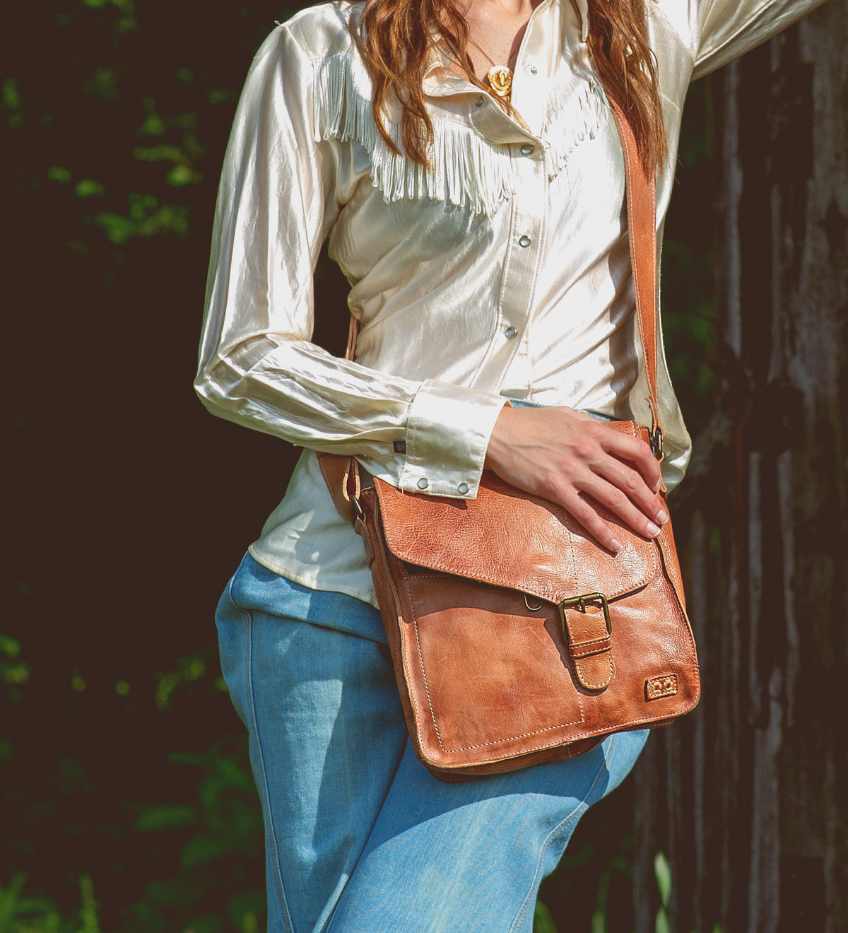 A woman wearing Venice Beach tan leather messenger bag from Bed Stu.