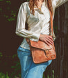A woman wearing Venice Beach tan leather messenger bag from Bed Stu.