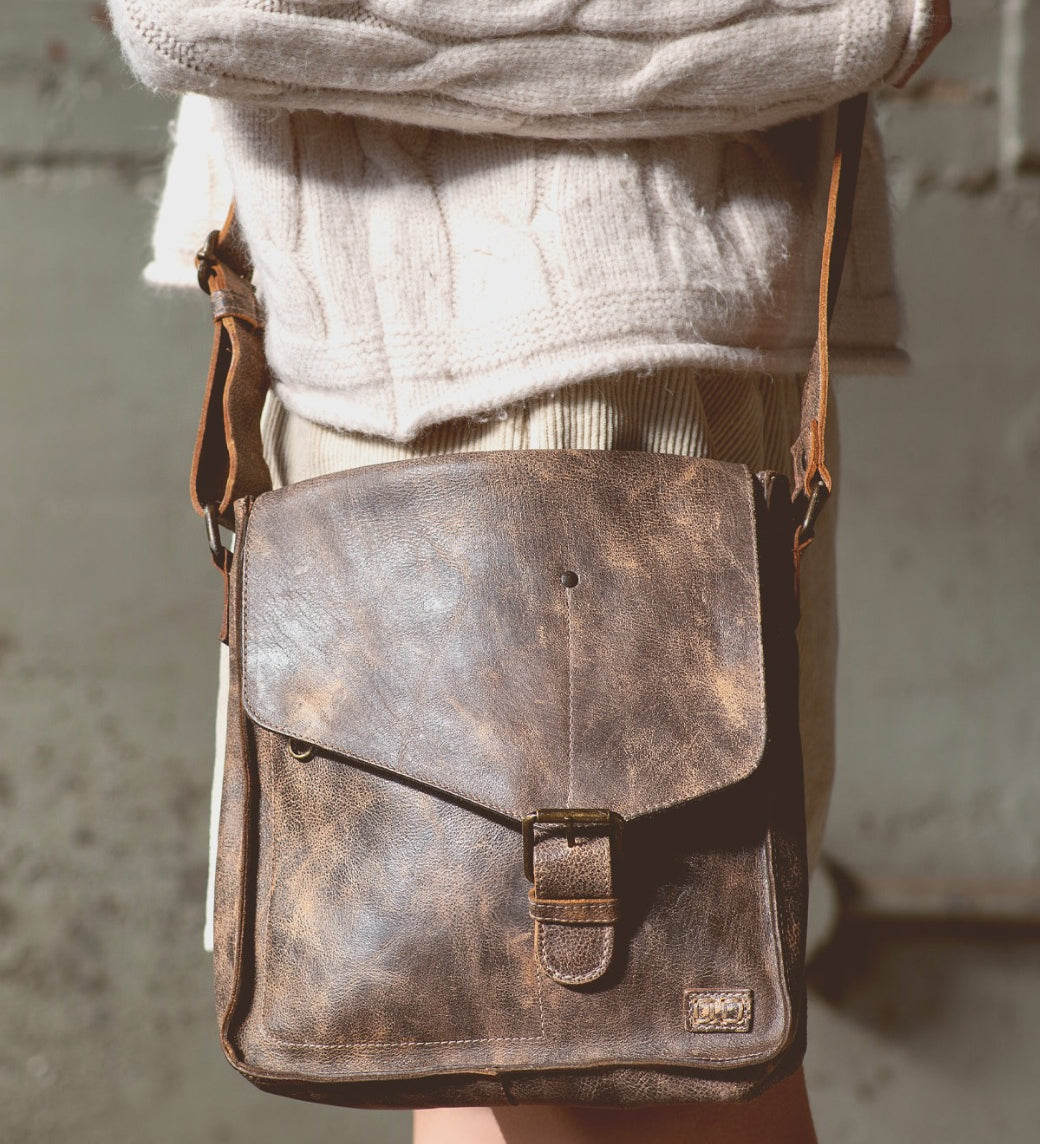 A woman wearing Venice Beach teak leather bag from Bed Stu.