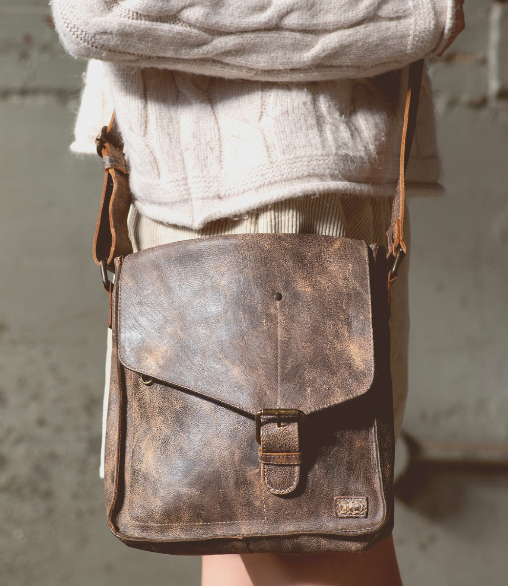 A woman wearing Venice Beach teak leather bag from Bed Stu.