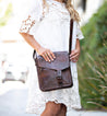 A woman in a white dress holding a vintage-inspired Bed Stu Venice Beach purse.