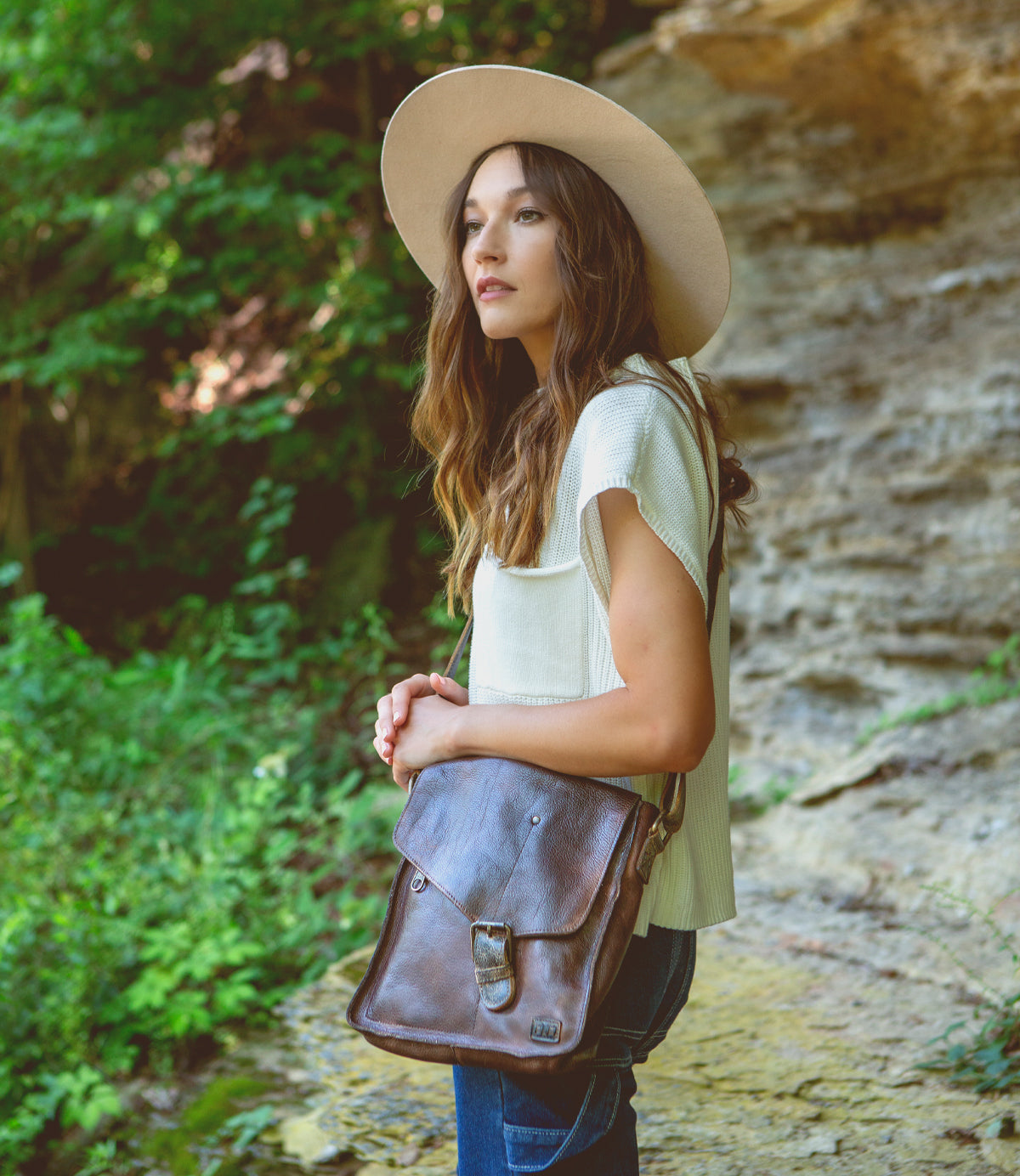 A woman wearing a hat and a Venice Beach teak leather bag by Bed Stu.