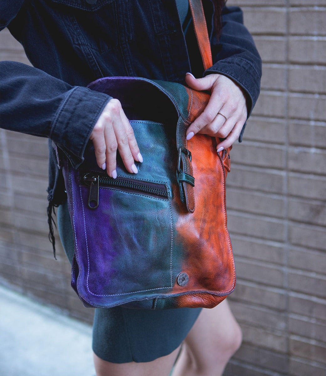 A woman is holding a colorful Bed Stu Venice Beach leather bag.