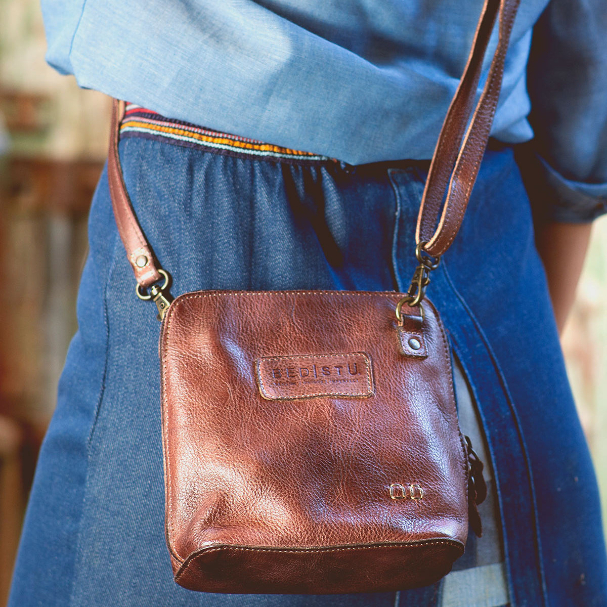 A woman is holding a Bed Stu Ventura leather cross body bag.