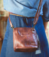 A woman is holding a Bed Stu Ventura leather cross body bag.
