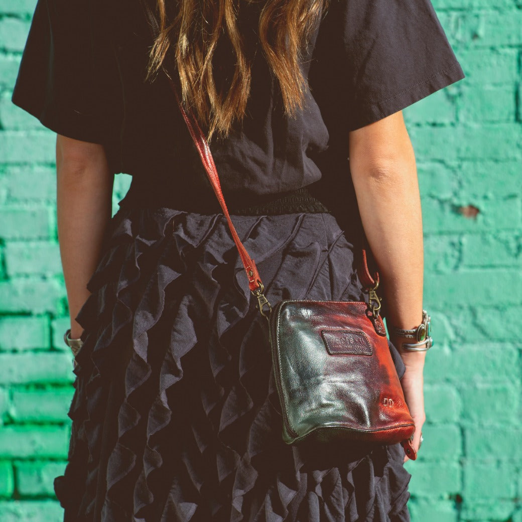 A woman wearing a black shirt and black skirt with a Bed Stu Ventura cross body bag.