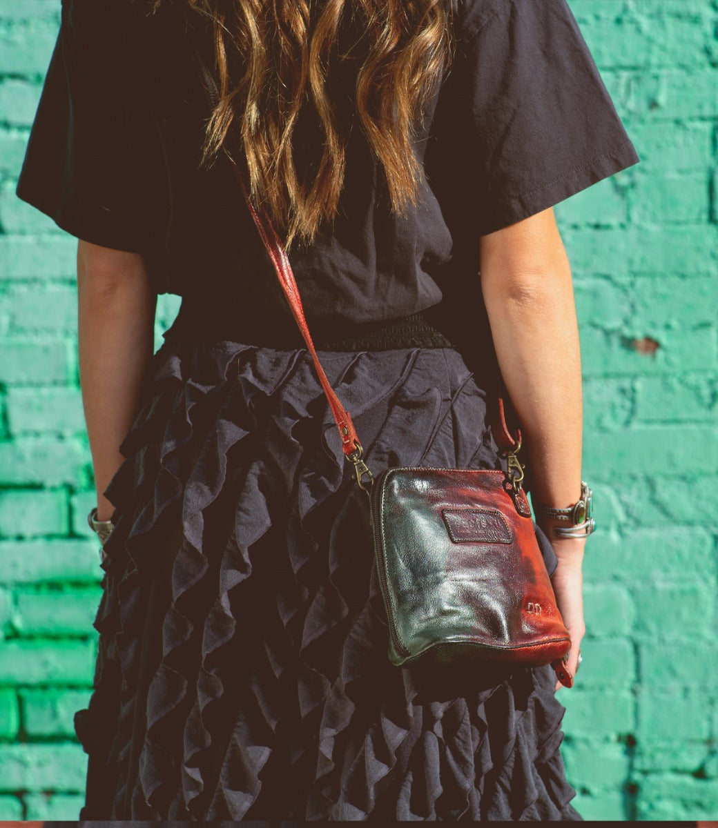 A woman wearing a black shirt and black skirt with a Bed Stu Ventura cross body bag.