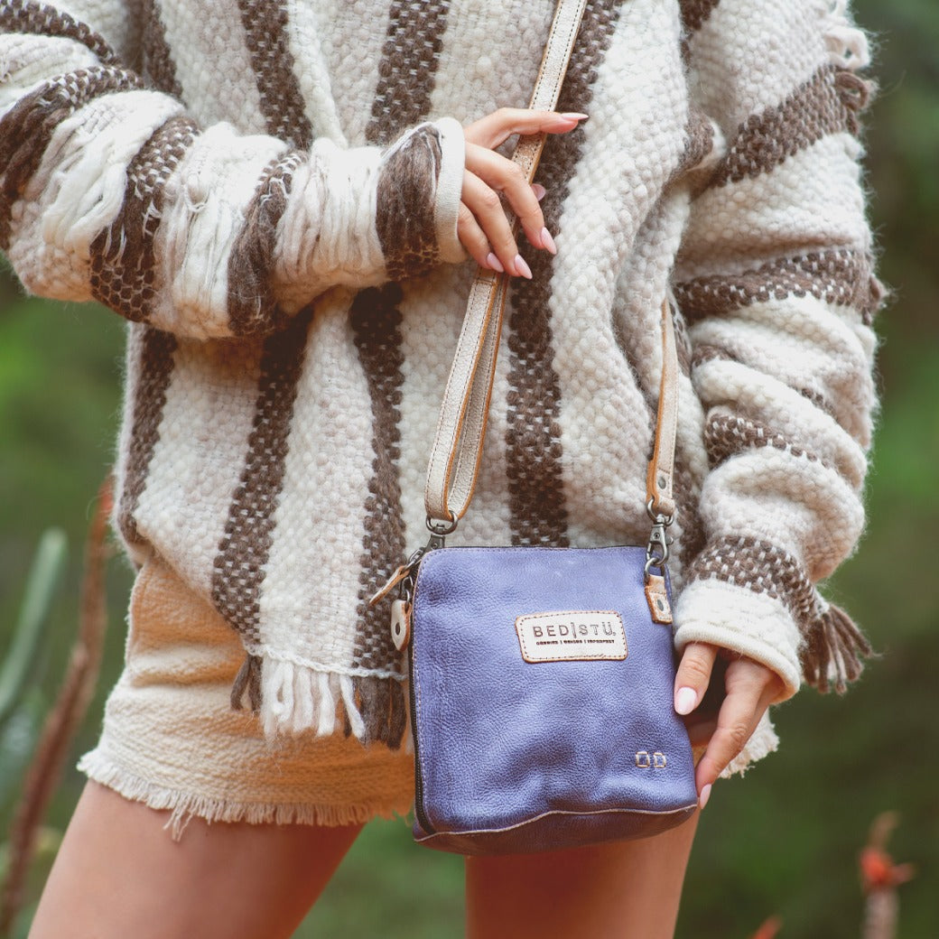A woman wearing a Ventura sweater and Bed Stu striped sweater holding a purse.