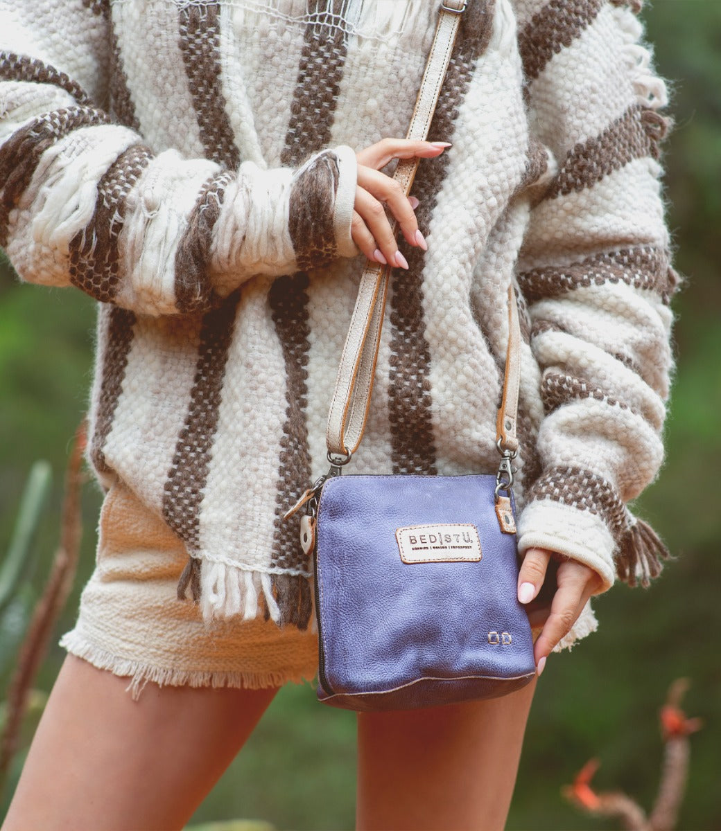 A woman wearing a Ventura sweater and Bed Stu striped sweater holding a purse.