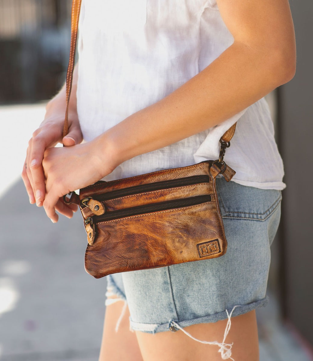 A woman wearing denim shorts and a Bed Stu Viana leather crossbody bag.