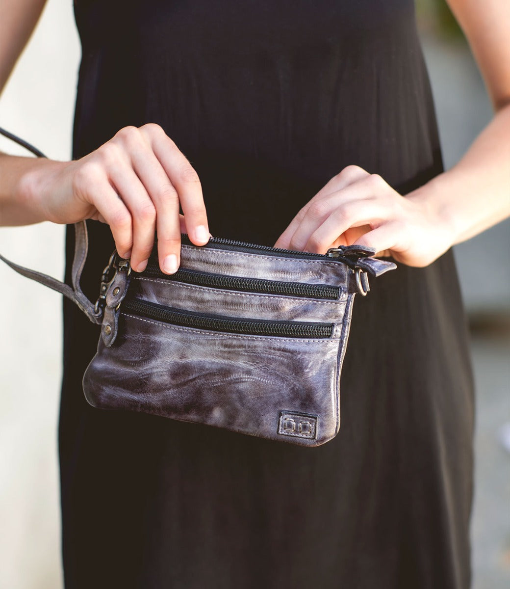 A woman wearing a black dress holding a Bed Stu Viana purse.