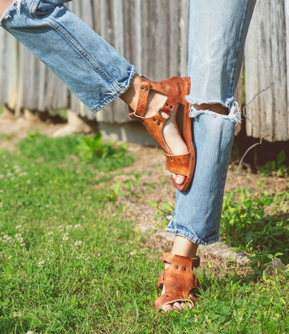 A woman wearing Voleta Bed Stu sandals in front of a wooden fence.