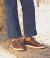 A person standing in front of a tree wearing jeans and a pair of Bed Stu Wizard sneakers.