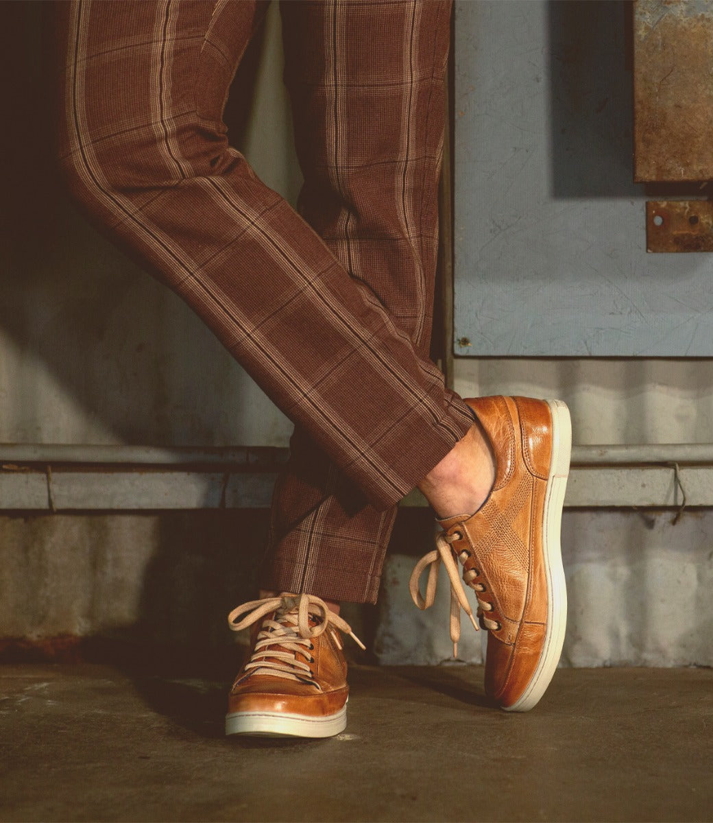 A person wearing brown pants and a pair of Bed Stu Wizard shoes.