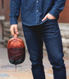 A man in jeans holding a Bed Stu Yatra leather bag.