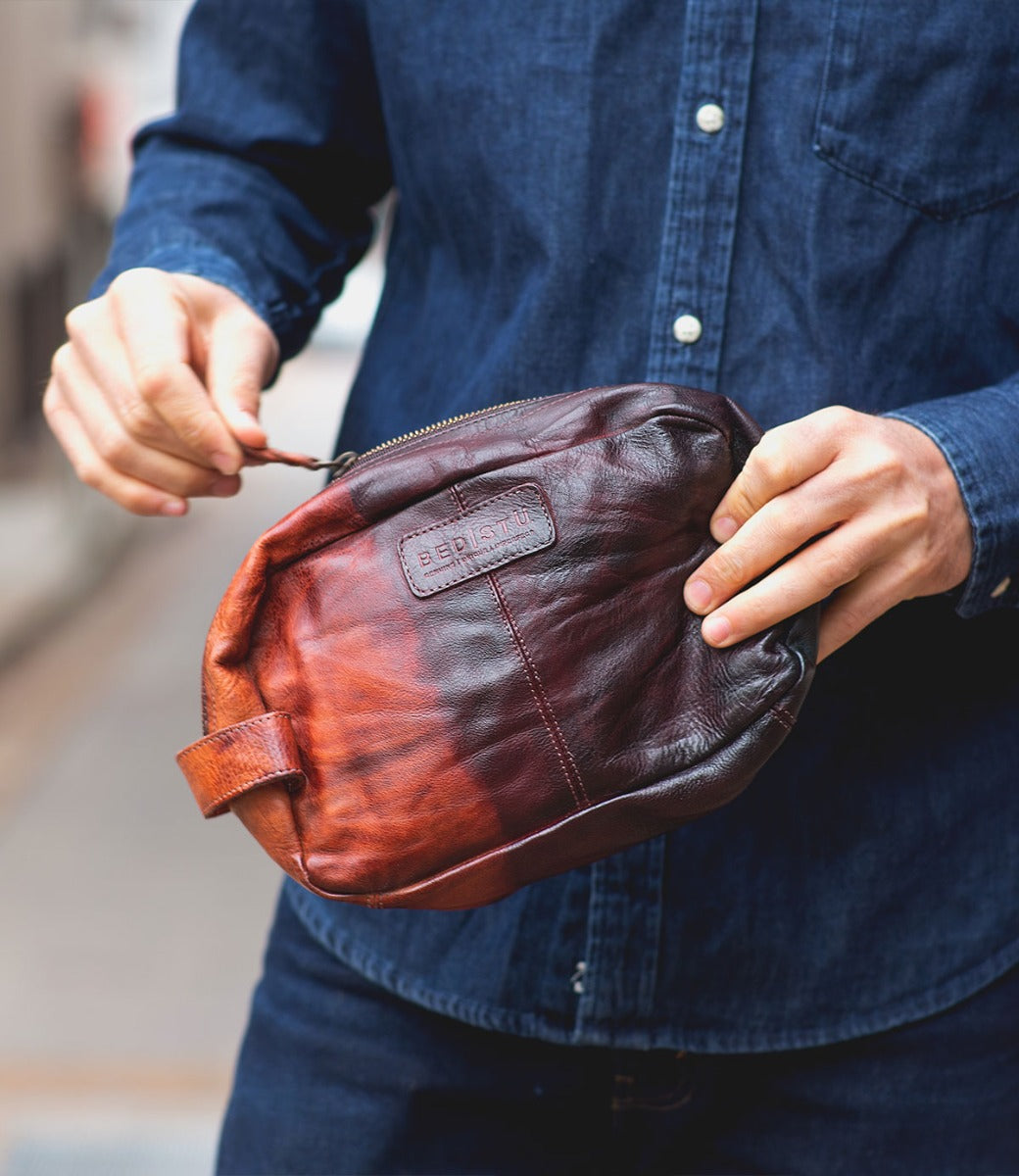 A man holding a Yatra toiletry bag from Bed Stu.