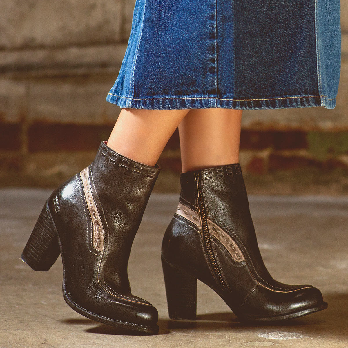 A woman in a denim skirt is wearing Bed Stu leather ankle boots.