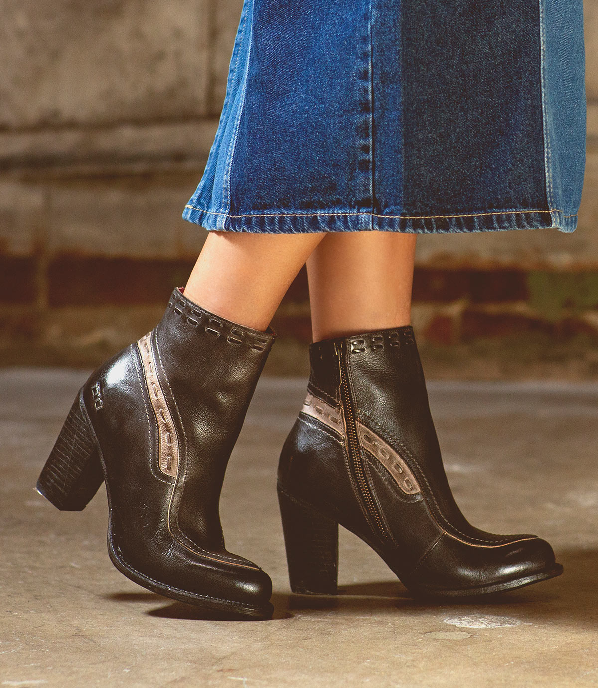 A woman in a denim skirt is wearing Bed Stu leather ankle boots.