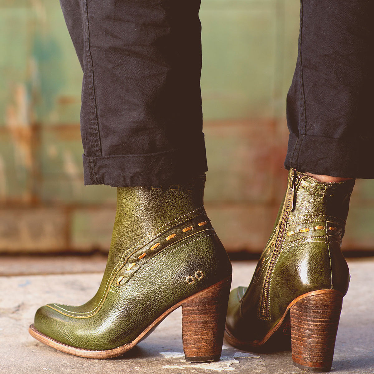 A woman wearing green leather Yuno ankle boots by Bed Stu with a heel.