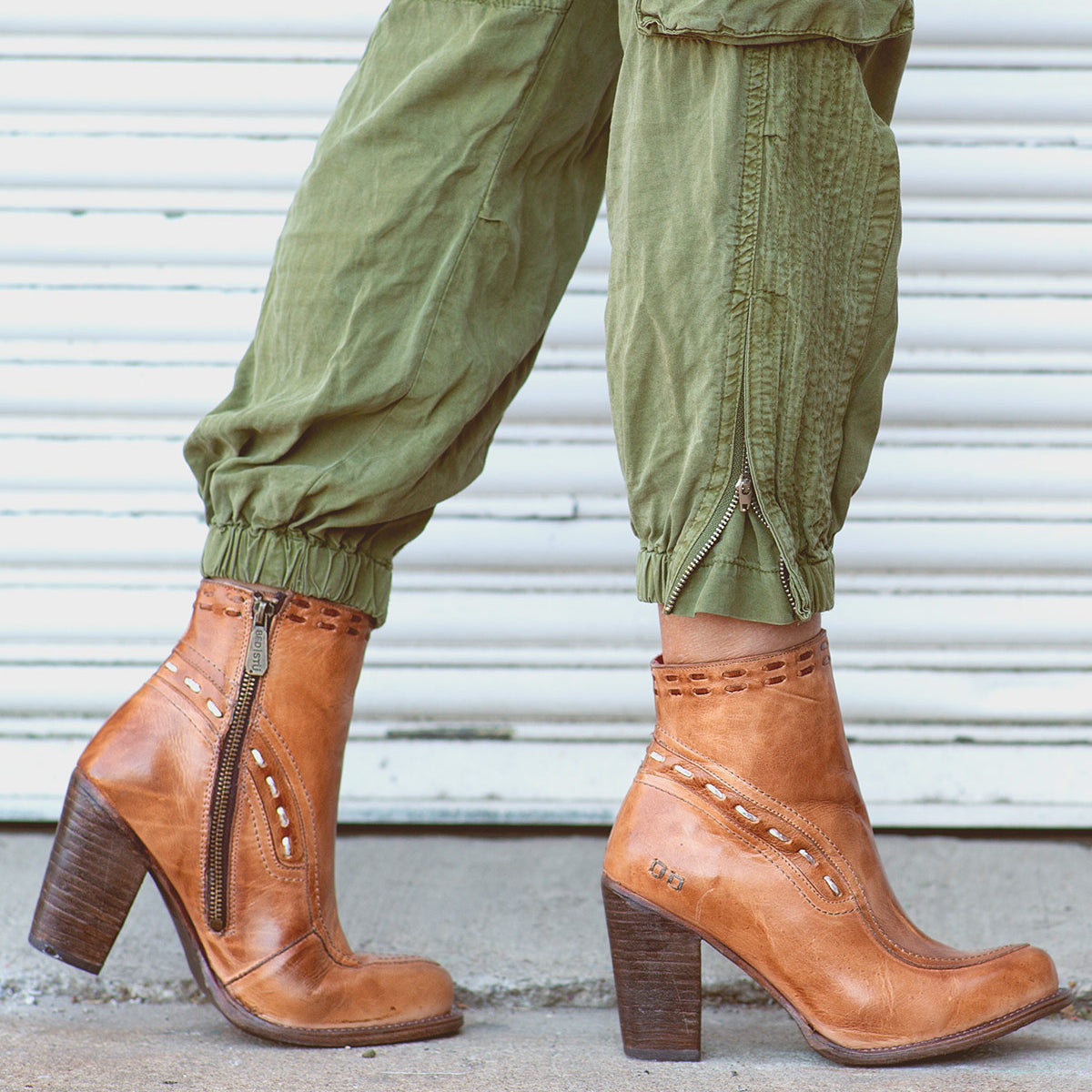 A woman wearing green Yuno pants and Bed Stu ankle boots made of leather.