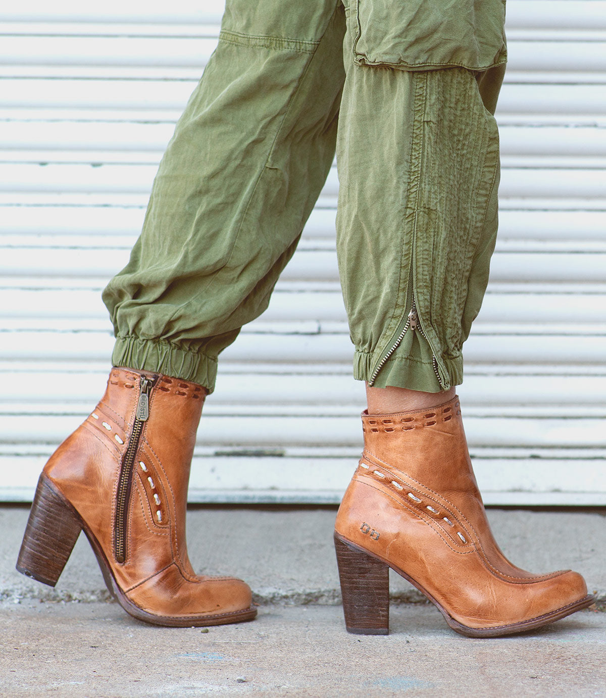 A woman wearing green Yuno pants and Bed Stu ankle boots made of leather.