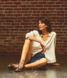 A woman sitting on the floor wearing her Yurisa vegetable tanned leather by Bed Stu.