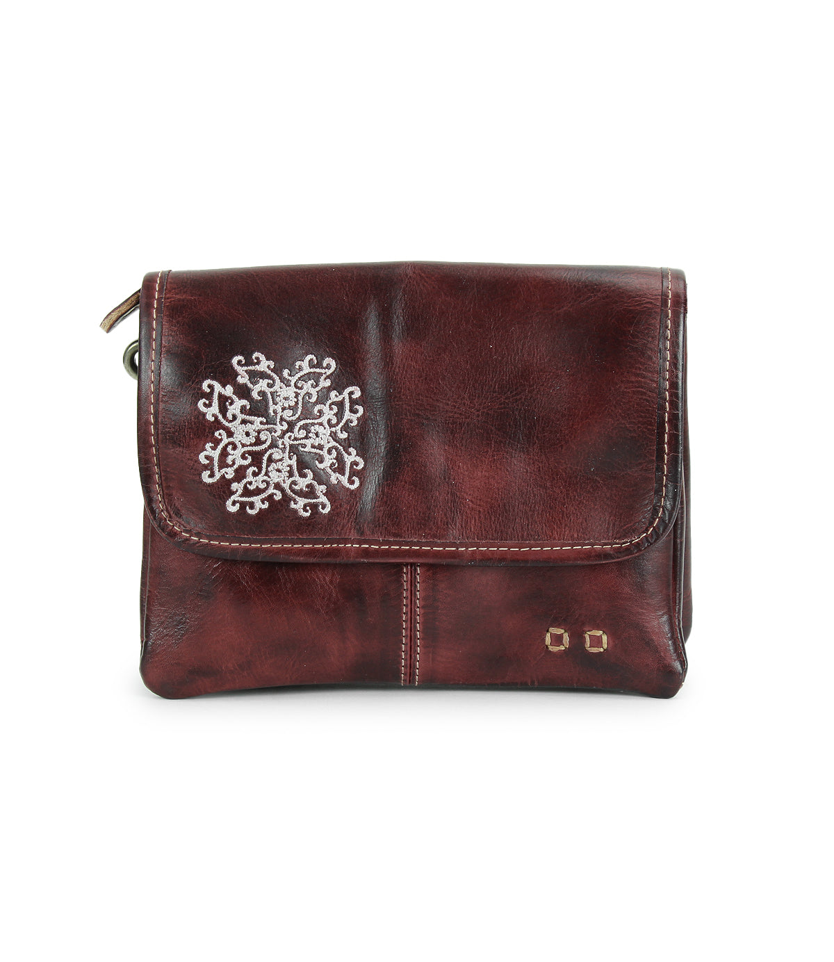 The Bed Stu Ziggy JB is a dark brown leather clutch featuring a silver snowflake design, two small gold studs on the front flap, and delicate embroidered details for an elegant touch.