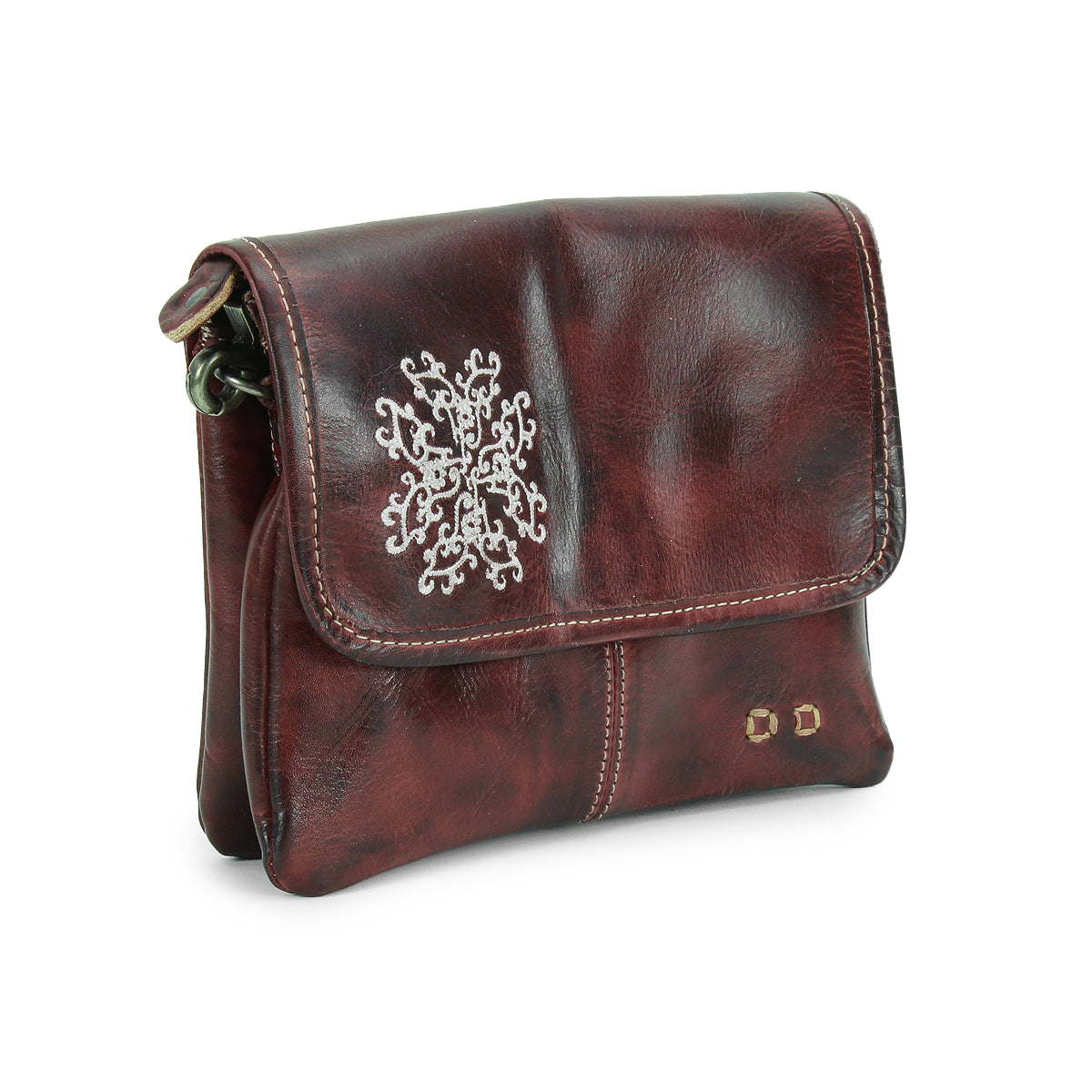 The Ziggy JB by Bed Stu is a small, dark brown leather crossbody bag featuring a flap closure, white embroidered details, and two brass rivets on the front.