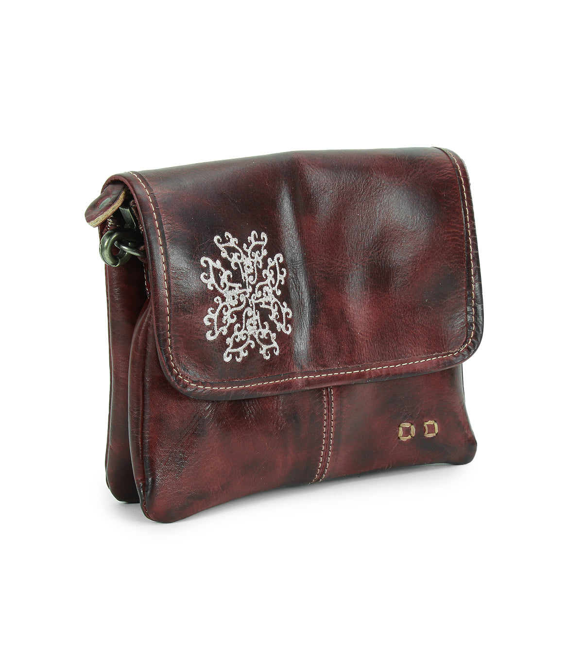 The Ziggy JB by Bed Stu is a small, dark brown leather crossbody bag featuring a flap closure, white embroidered details, and two brass rivets on the front.