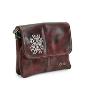 The Ziggy JB by Bed Stu is a small, dark brown leather crossbody bag featuring a flap closure, white embroidered details, and two brass rivets on the front.