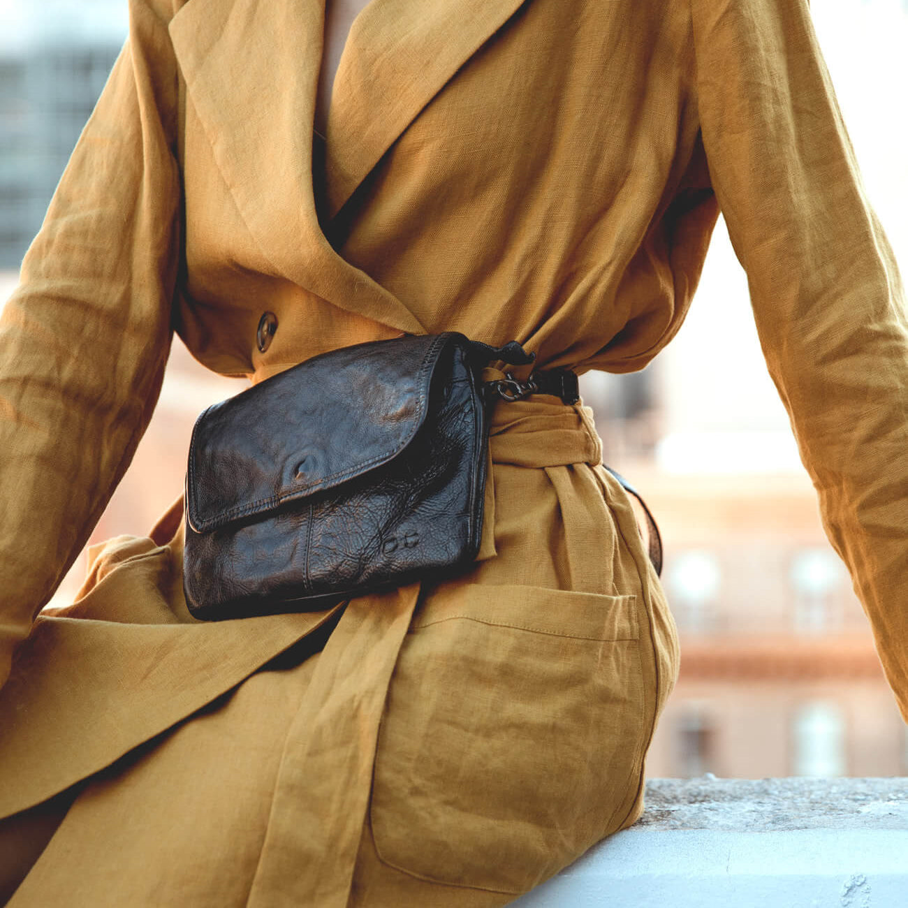 A woman wearing a black Ziggy bag and yellow coat.