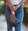 A woman wearing jeans and a Bed Stu black and brown Ziggy clutch.