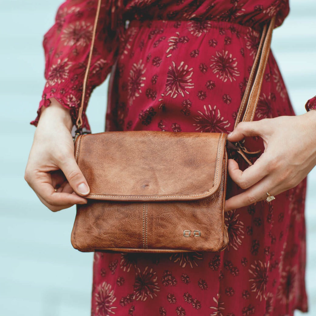 A woman in red dress holding a Ziggy cross body bag by Bed Stu.