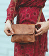 A woman in red dress holding a Ziggy cross body bag by Bed Stu.