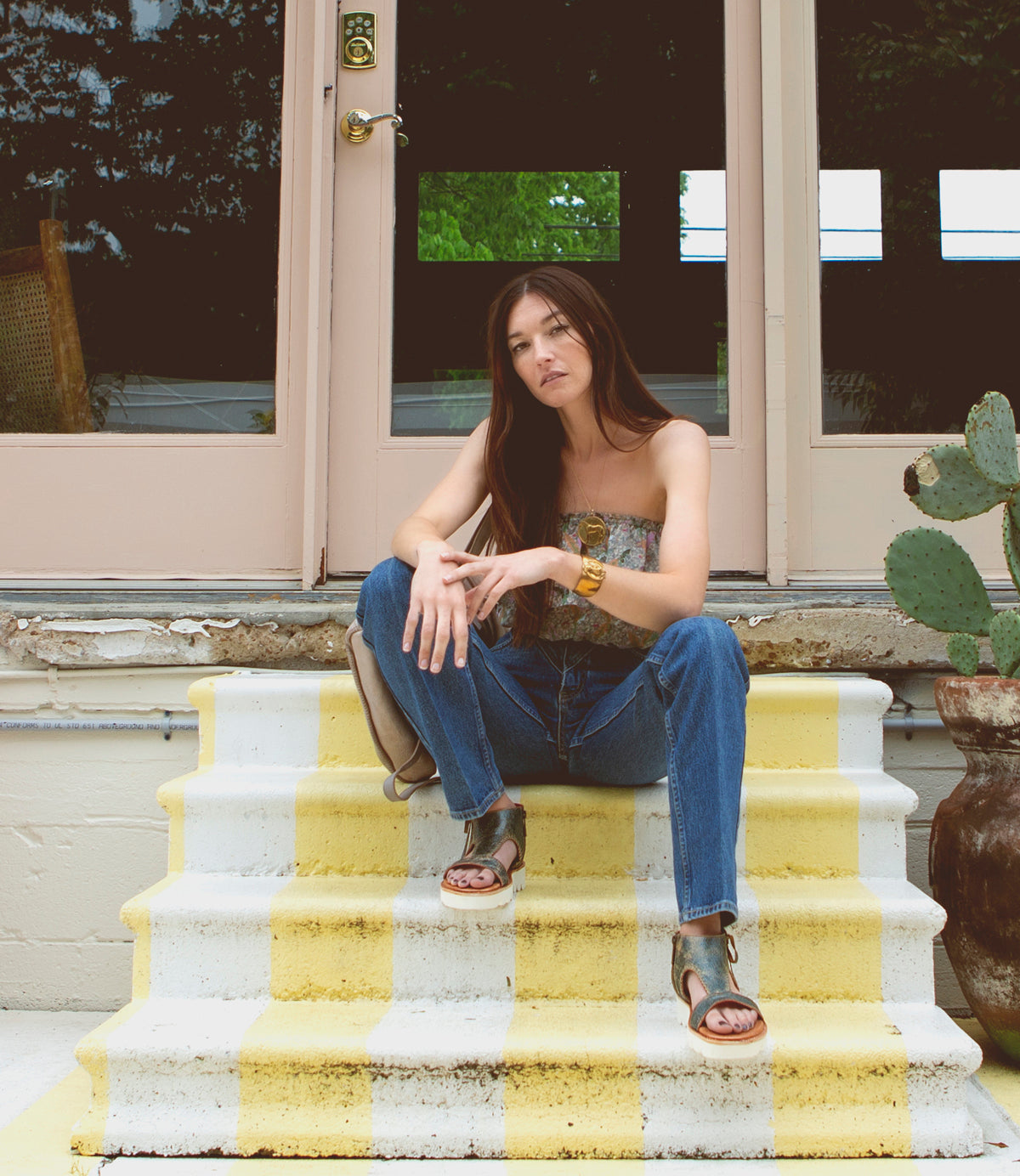 A woman sitting on a set of stairs, wearing the Bed Stu Zoe II.